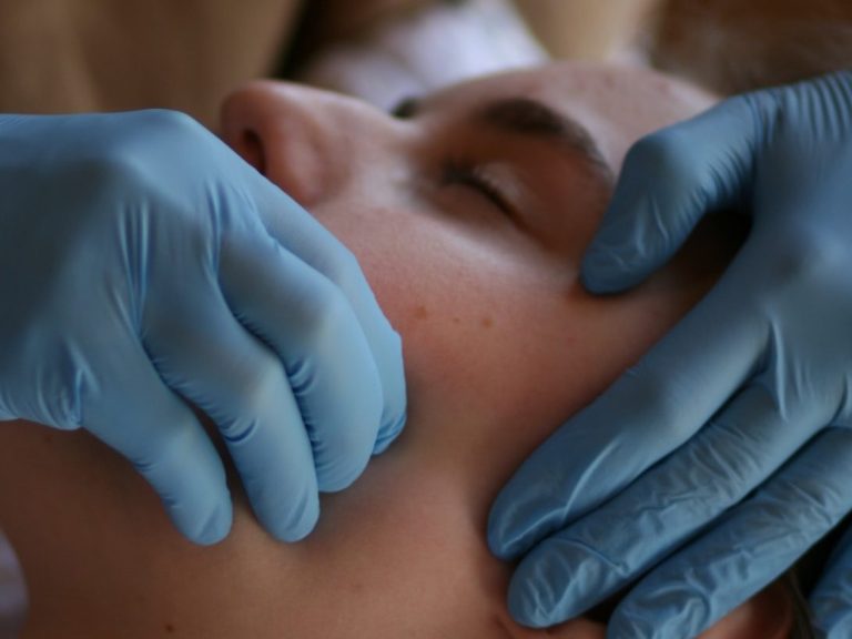Eine Person erhält eine Gesichtsbehandlung mit gloved Händen.