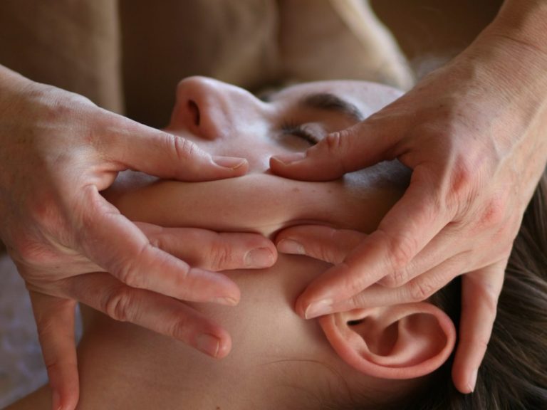 Eine Person erhält eine Gesichtsmassage durch eine andere Person.