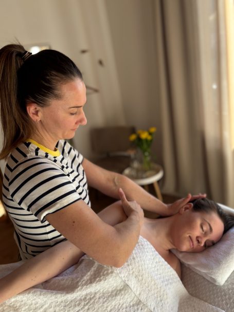 Eine Frau erhält eine Massage, während eine andere sie sanft behandelt.